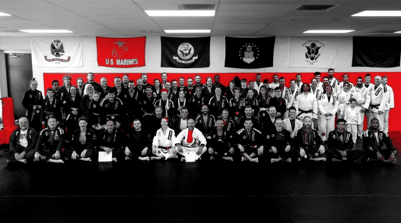 The JGMMA team lined up on the mats in West Chester, in front of the red wall and flags